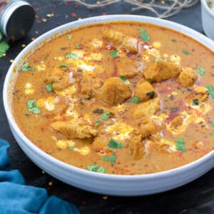 Chicken Curry in a white bowl with few ingredients around.