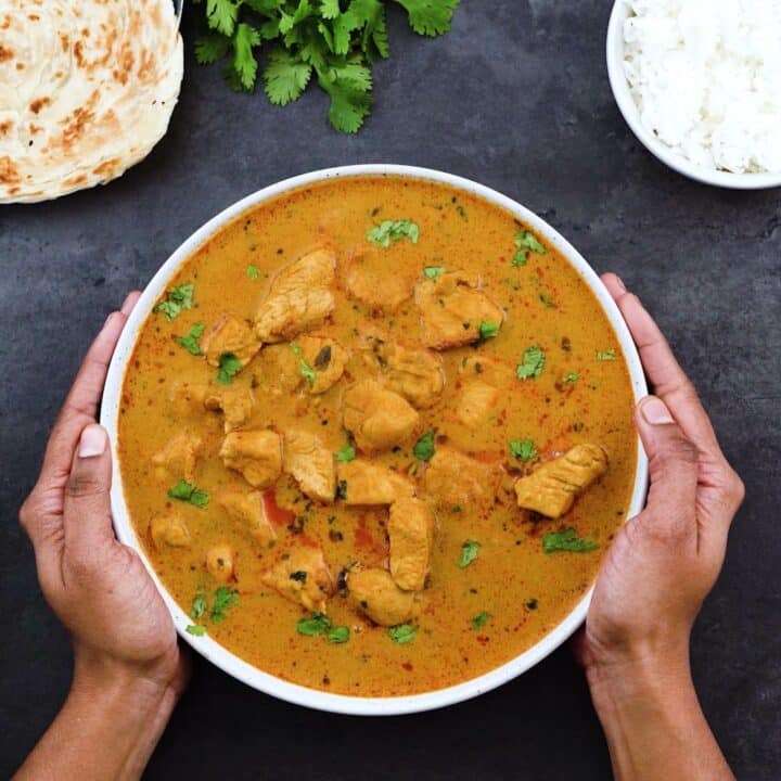 Serving Chicken Curry in a serving bowl with Paratha and rice alongside.