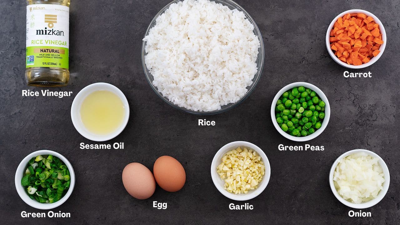 Ingredients for a chicken fried rice recipe arranged on a grey table.