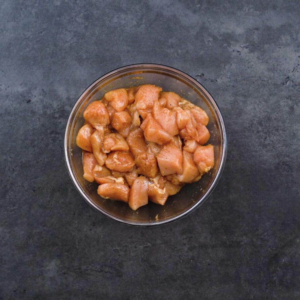 A bowl containing chicken that has been marinated.