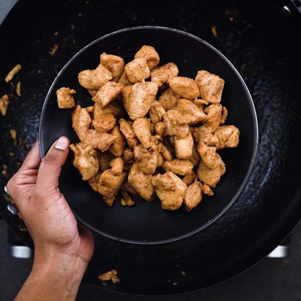 Stir fried chicken on a black plate.