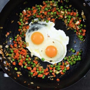 A wok containing eggs and stir-fried vegetables.