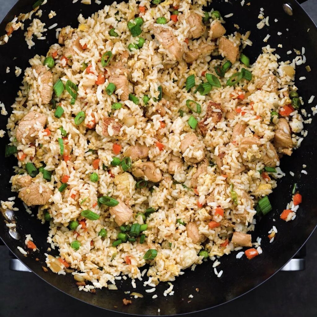 A wok containing Chicken Fried Rice garnished with green onions.