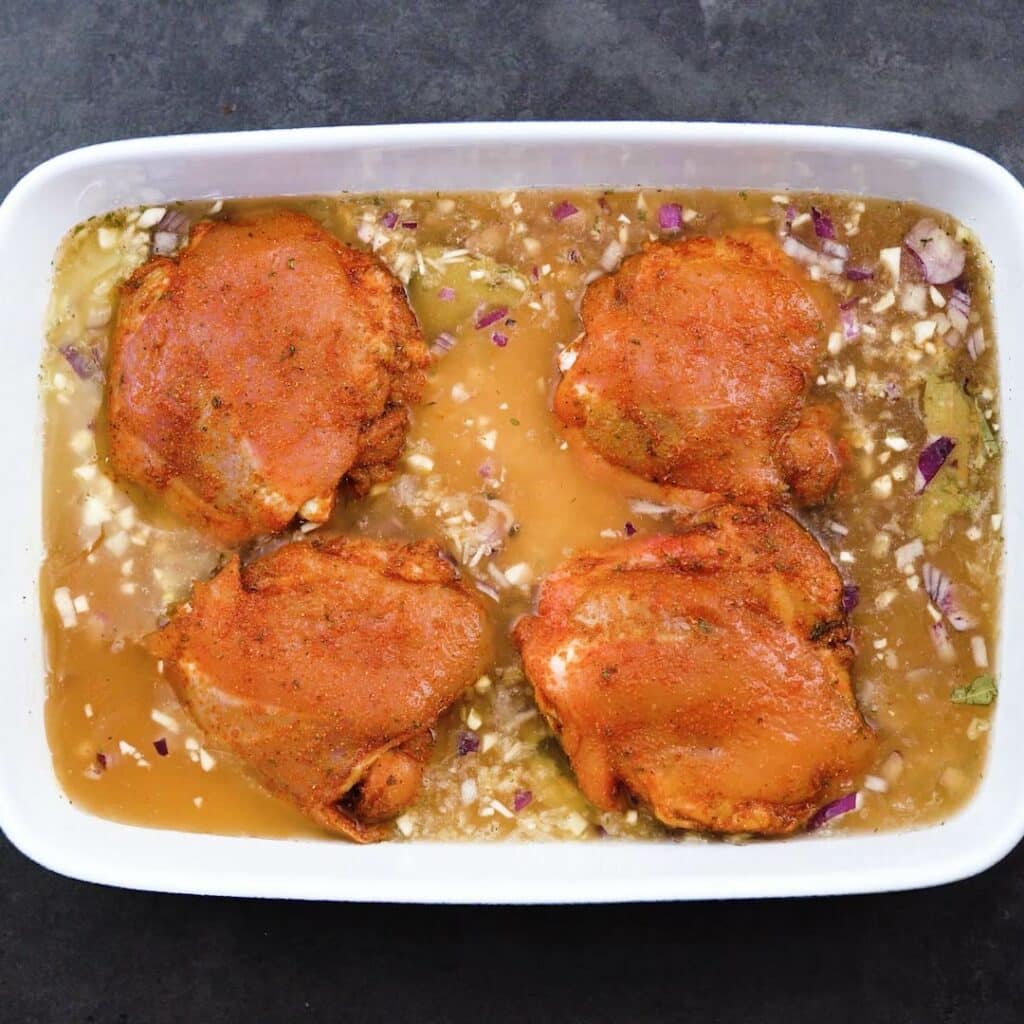 Chicken thighs with rice mixture in a baking pan.