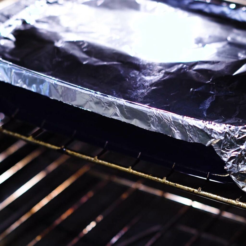 Chicken and rice baking inside the oven with foil covered.