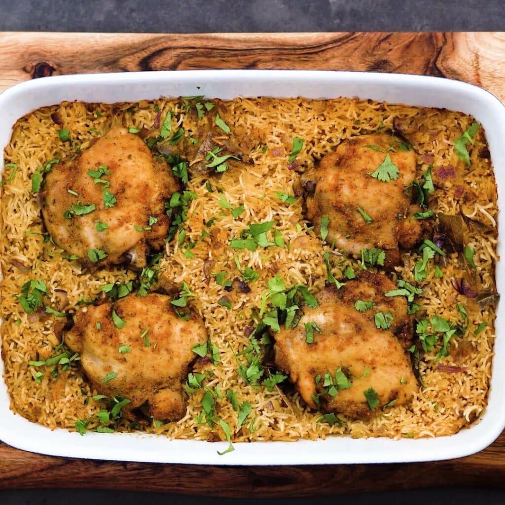 Baked Chicken and rice garnished with coriander leaves.