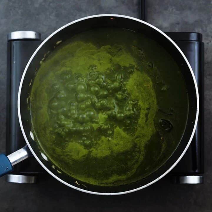 Saag curry is boiling in a pan.