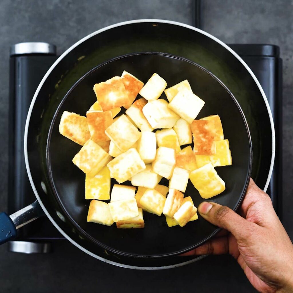 Adding fried paneer to the saag curry.