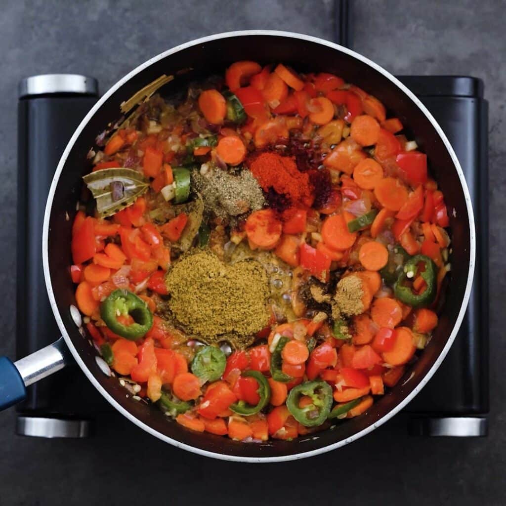 Veggies with chili seasoning in a pan.
