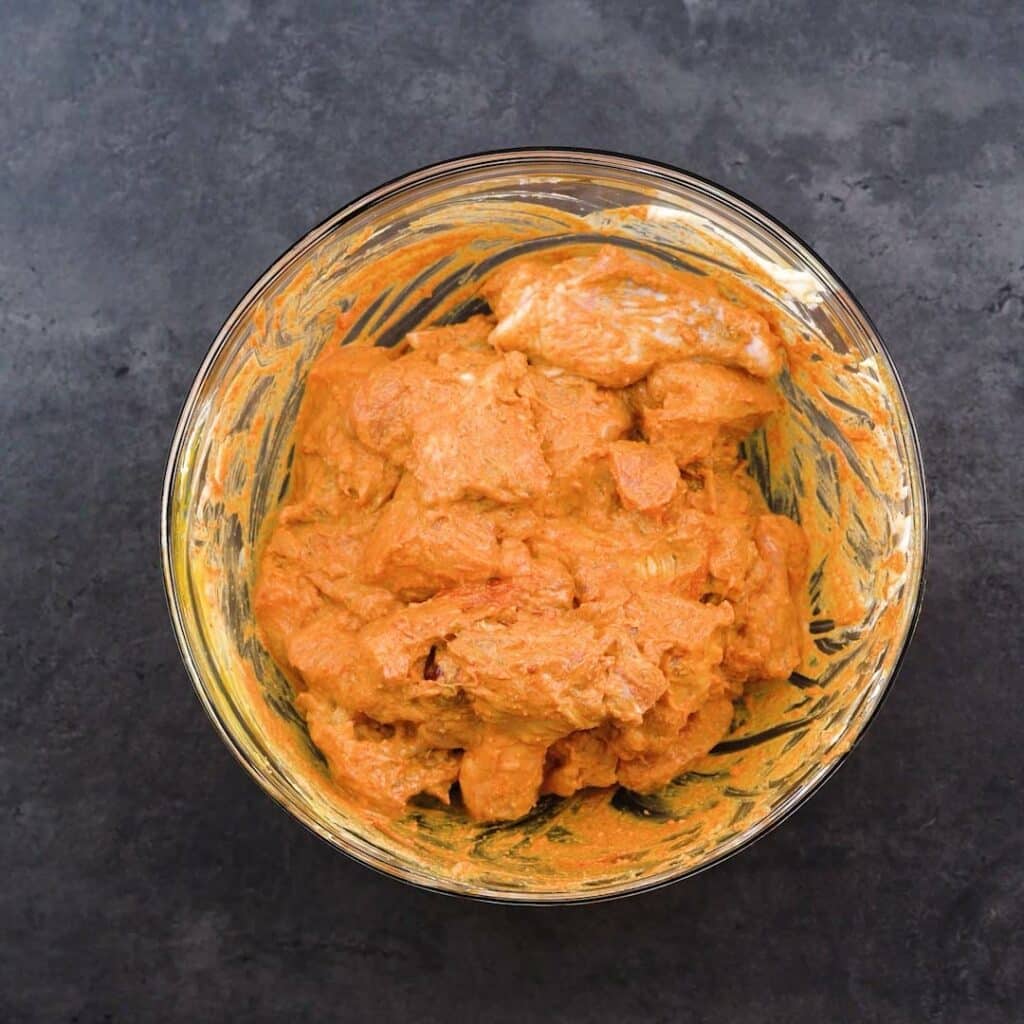 A bowl of chicken marinated with spices and yogurt.