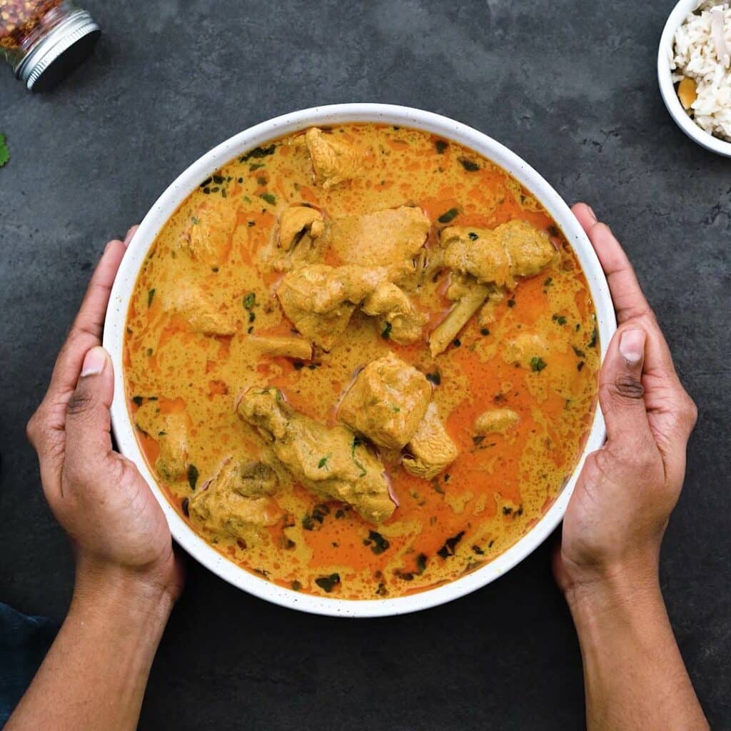 Serving Chicken Korma in a bowl with ghee rice alongside.