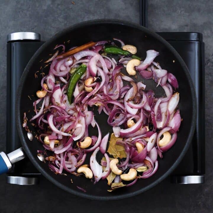 Sauteed Onion, cashews and whole Indian spices in a pan.