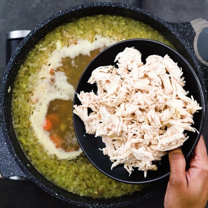 Adding shredded chicken to the soup.