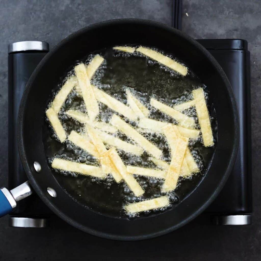 Corn tortilla stripes frying in oil.
