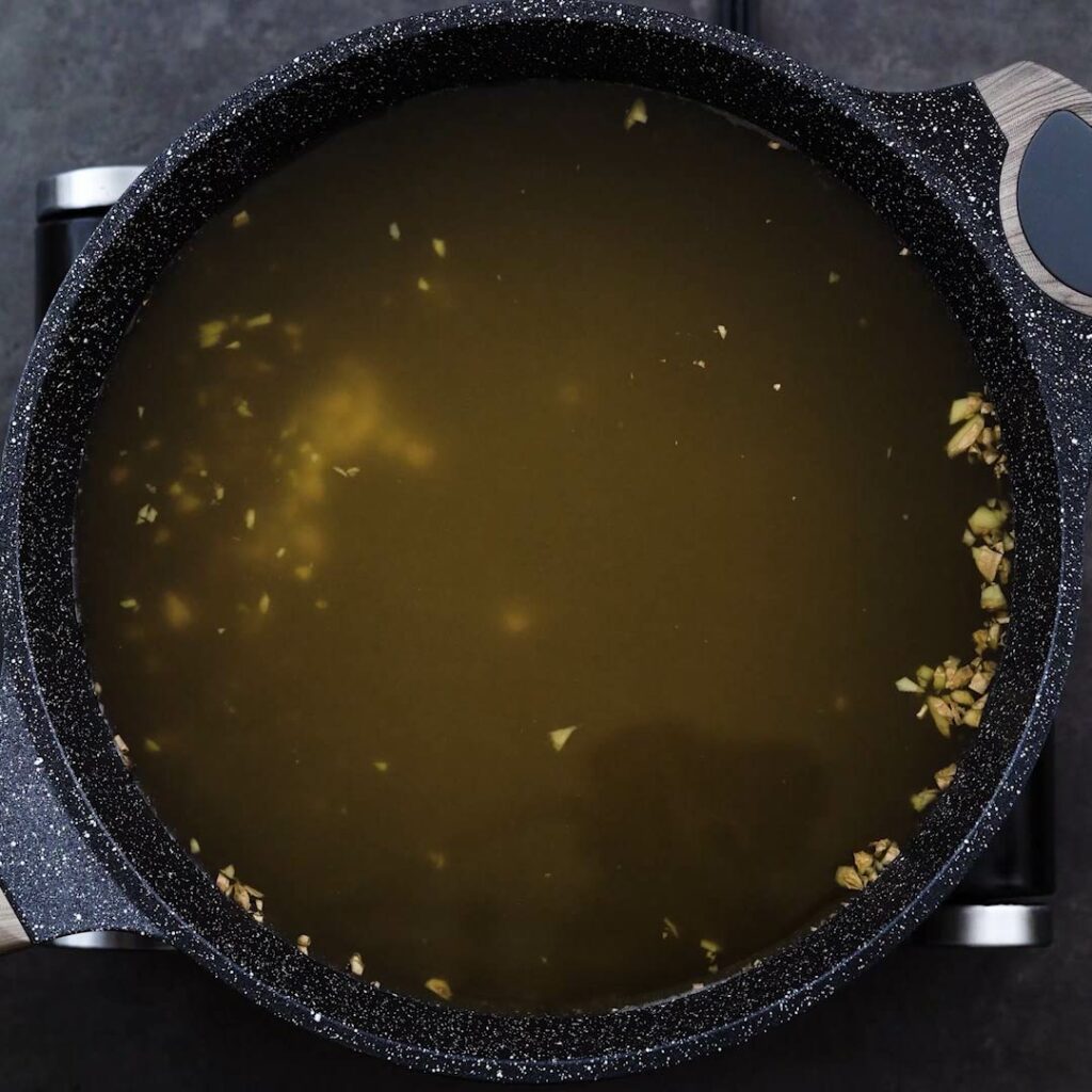 Chicken stock is getting heated up in a pot.