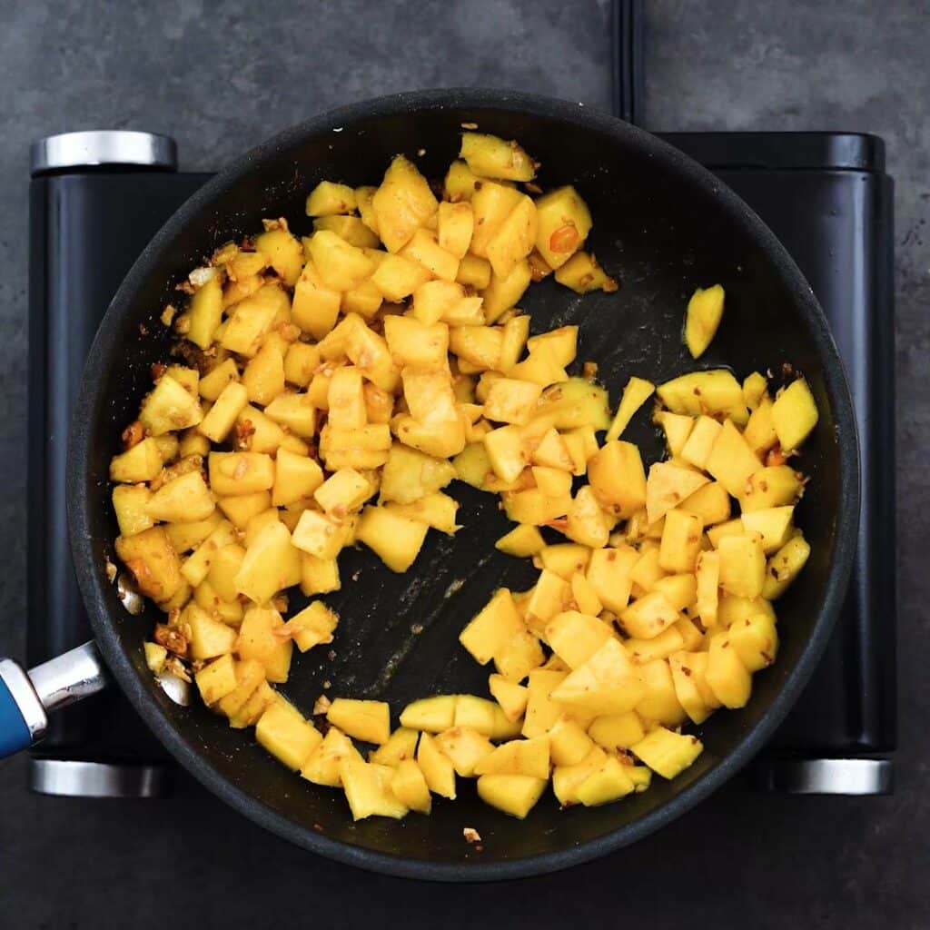 Diced ripe mangoes are coated with seasonings.