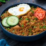 Nasi Goreng(Indonesian Fried Rice) in a blue bowl with fried eggs and veggies.