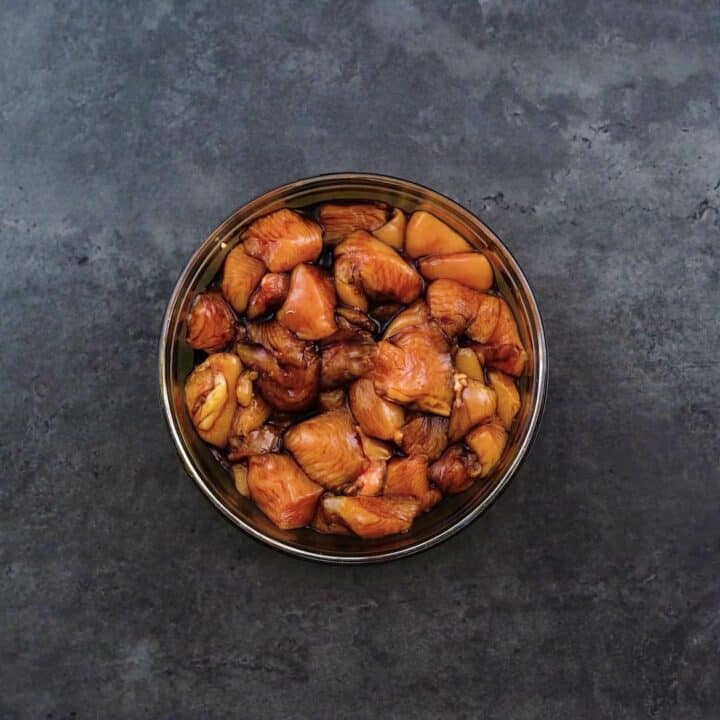 A bowl with marinated boneless chicken.