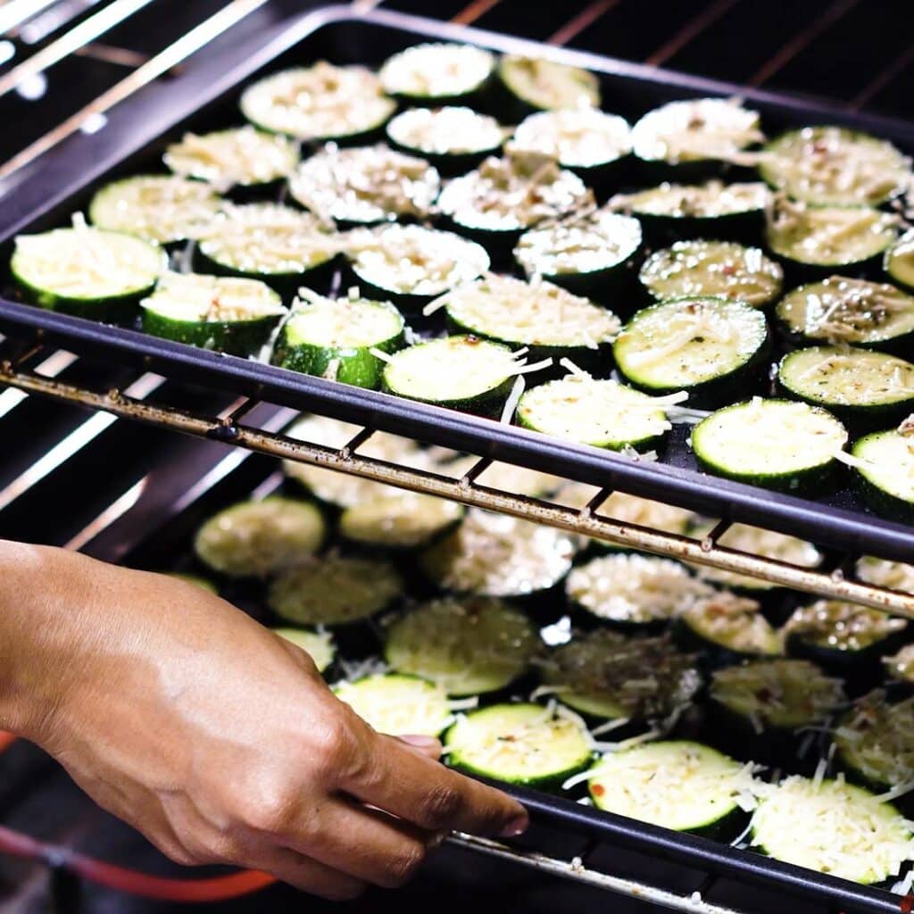 Placing the baking tray with zucchini inside the oven.