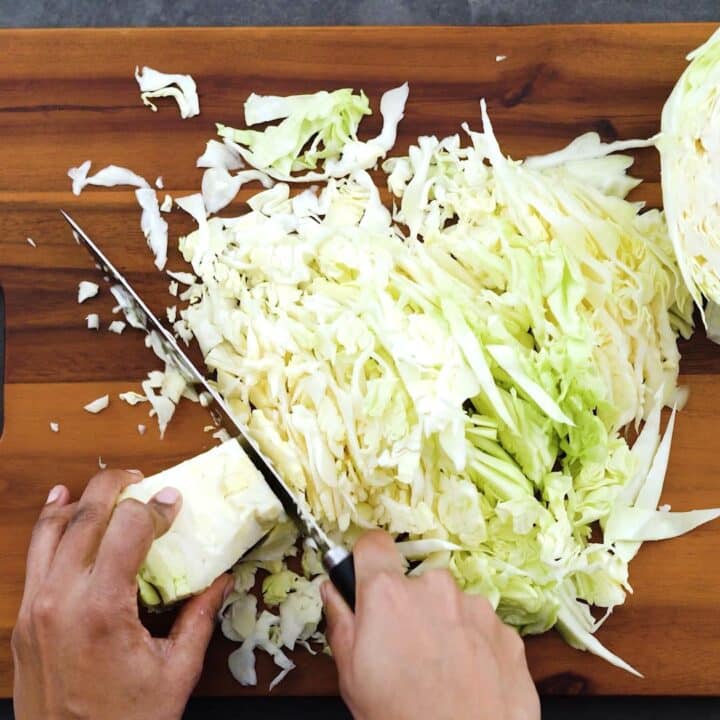 Chopping the cabbage on a cutting board.