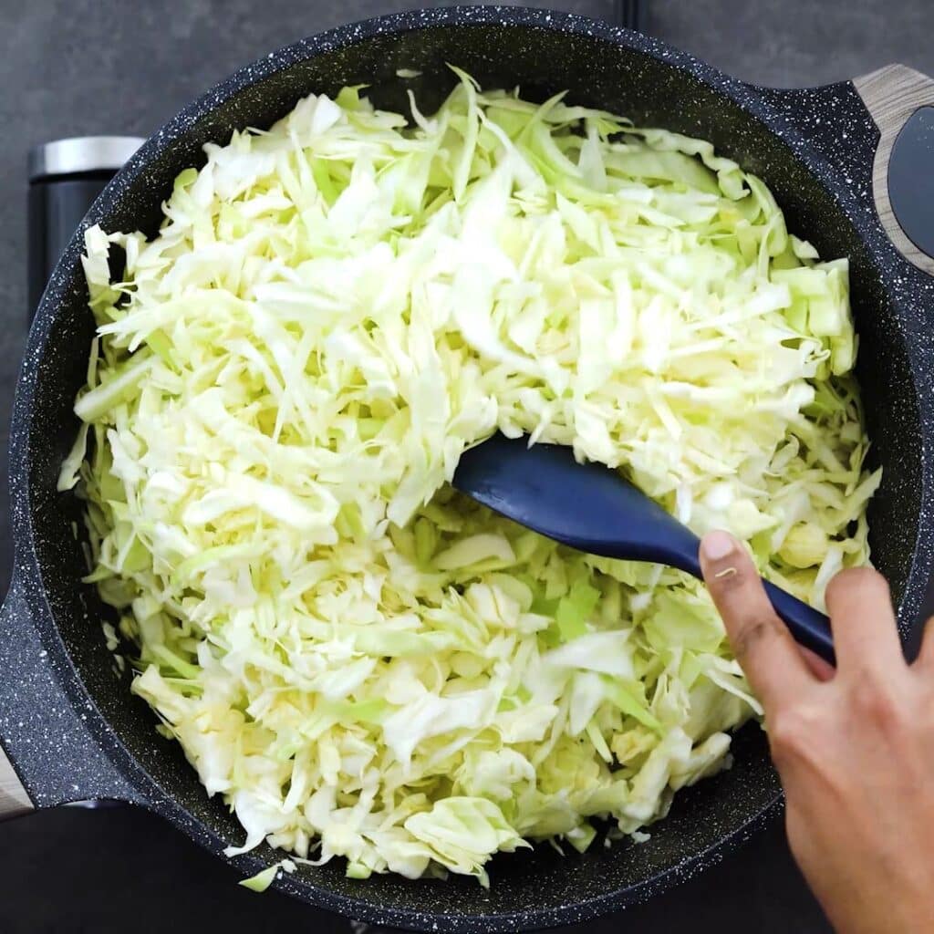 Sauteing the cabbage in a pan.