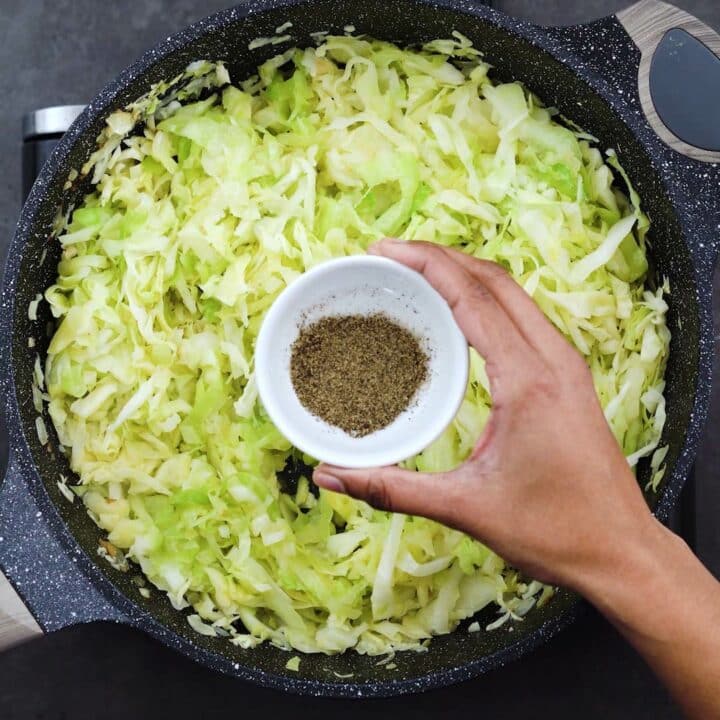 Seasoning the sauteed cabbage with black pepper.