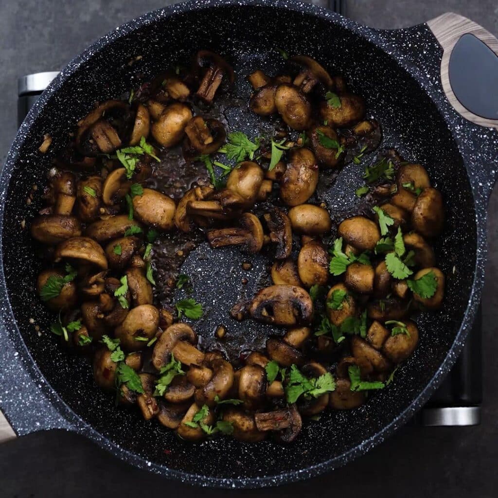 Sauteed Mushroom garnished with cilantro in a pan.