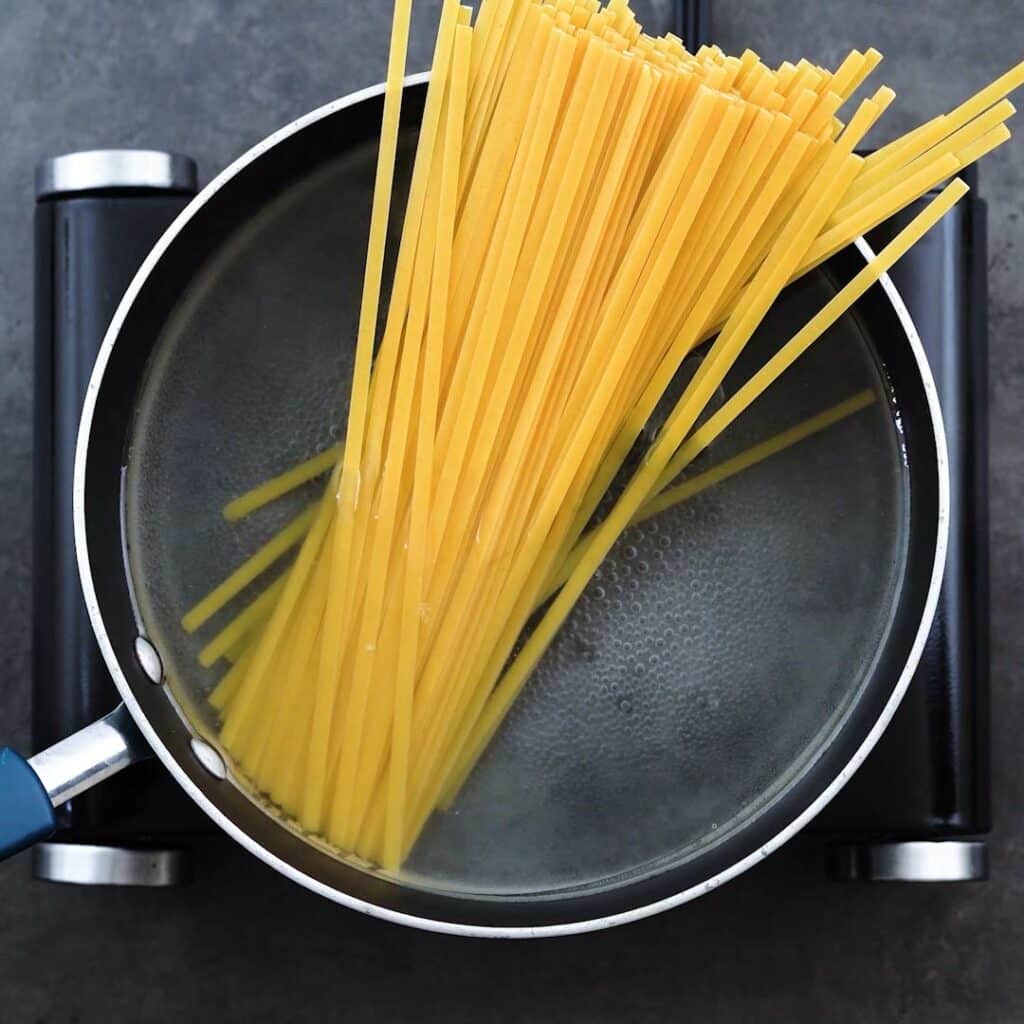 A pot with boiling water and fettuccine pasta.