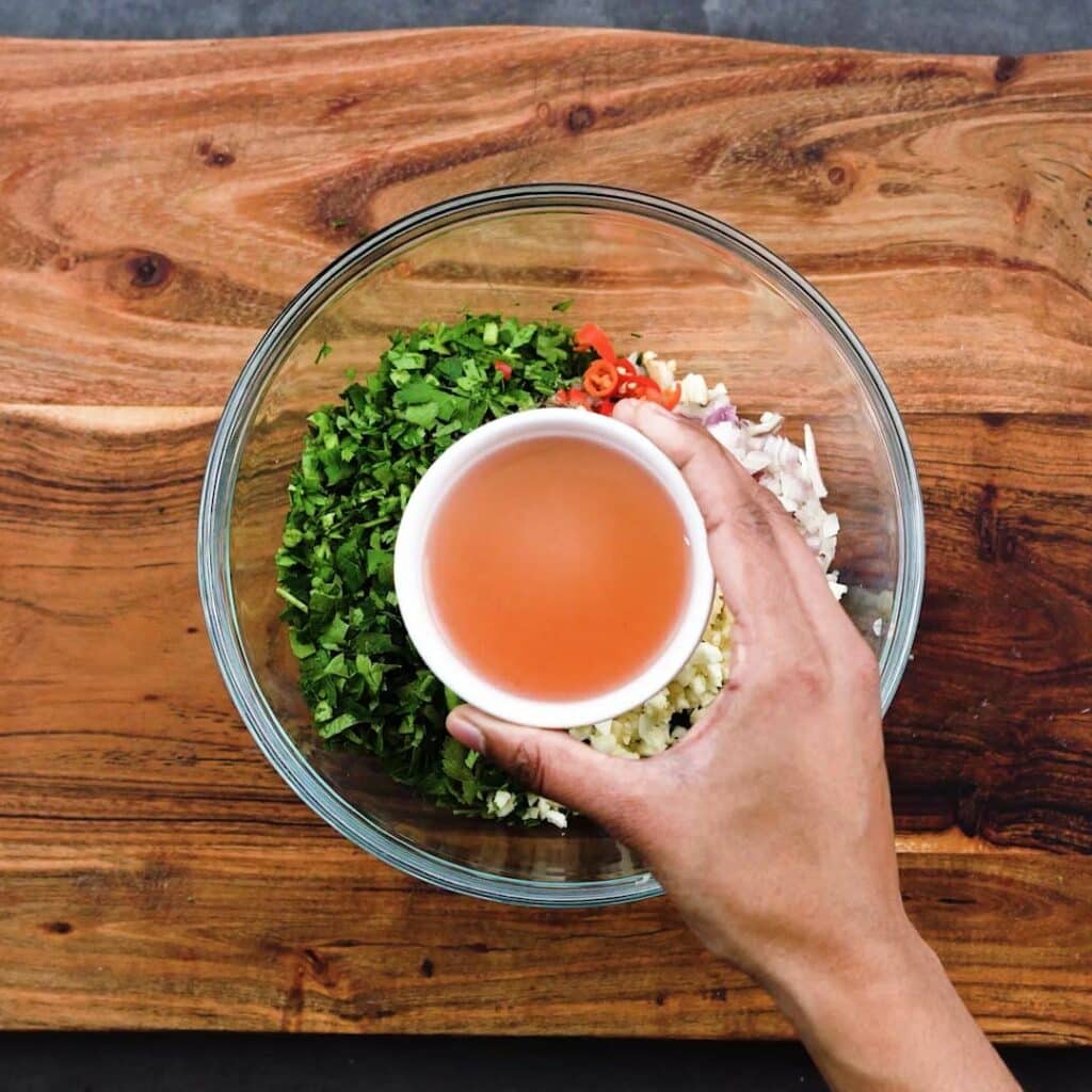 A hand holding a small cup with red wine vinegar.