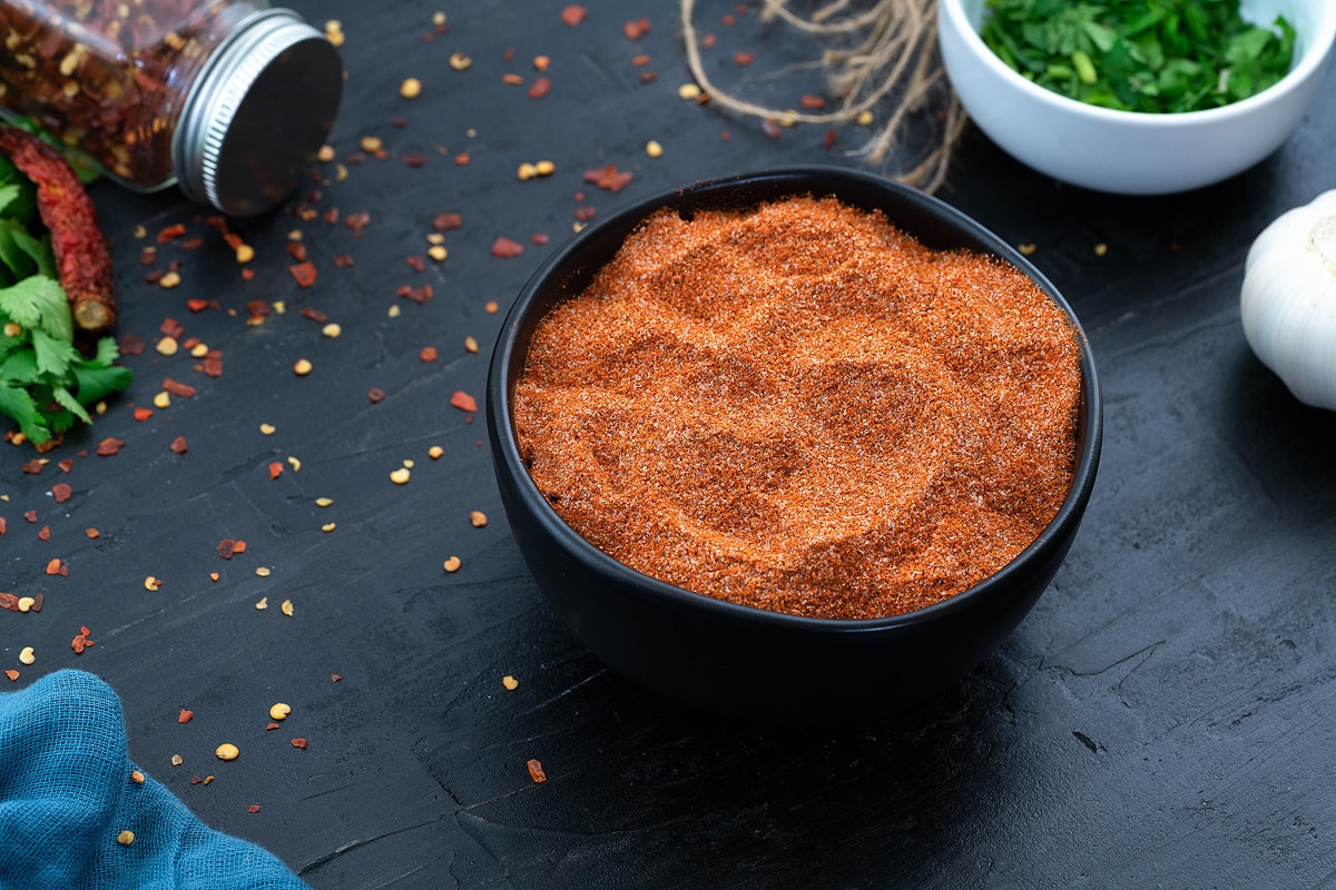 Fajita Seasoning in a black bowl with few ingredients scattered around.