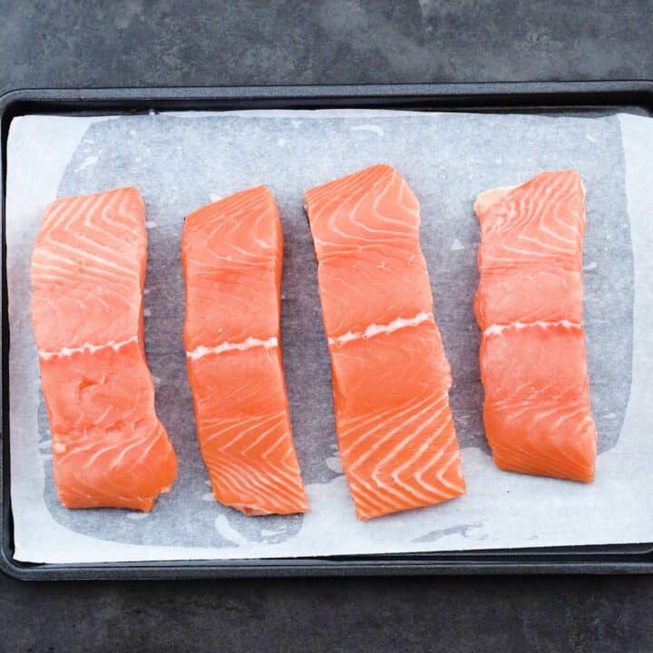 A baking tray with salmon fillets.