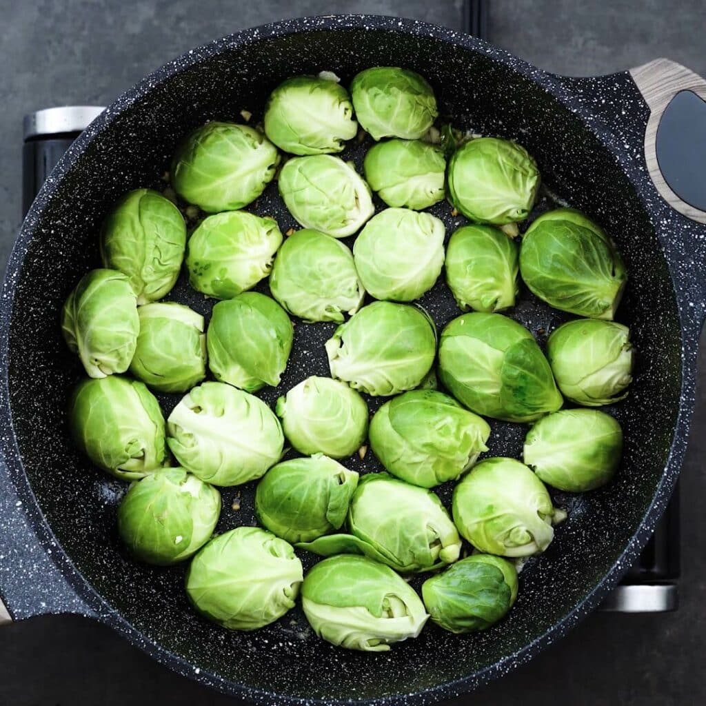 Brussels sprouts placed cut side down in a pan.