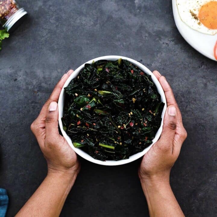 Serving the sauteed kale in a white bowl.