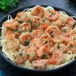 Shrimp Scampi in a black bowl with few ingredients scattered around.