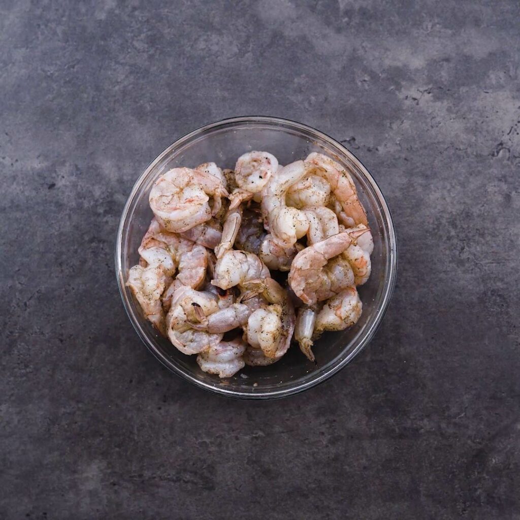 A bowl with shrimp seasoned with salt and pepper.