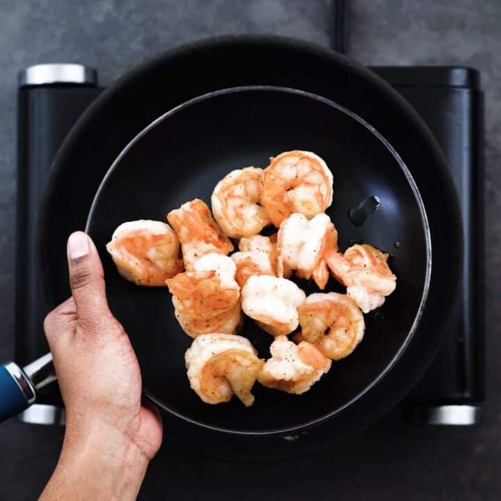 Showing Shallow fried shrimp that is placed on a black plate.