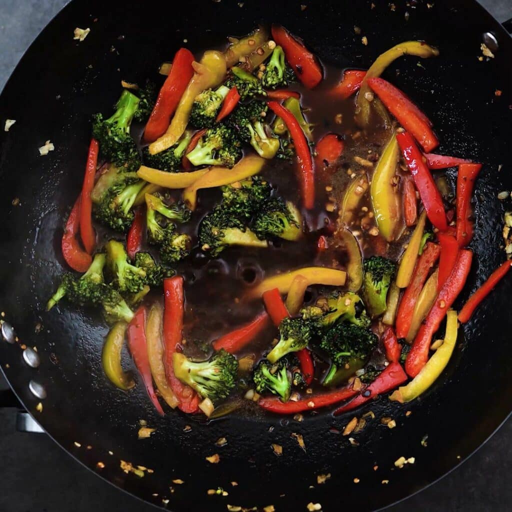 A wok with stir fried veggies and sauce.