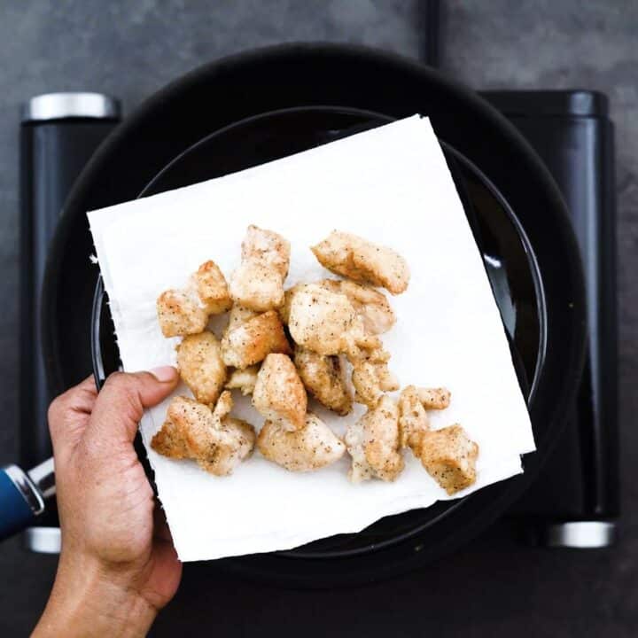 Showing fried chicken placed on a black plate with tissue paper.