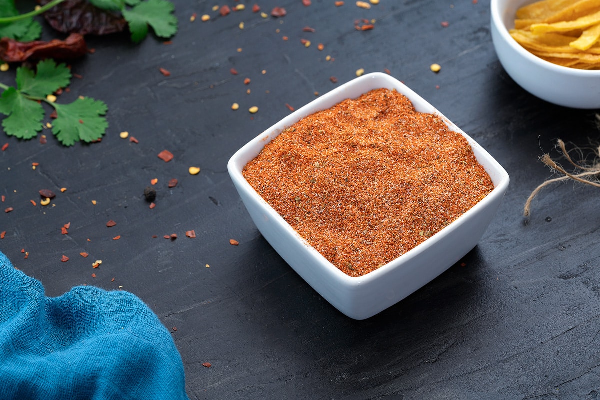 Taco Seasoning in a white square cup with few ingredients around.