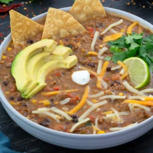 Turkey Chili in a white bowl with few ingredients scattered around.