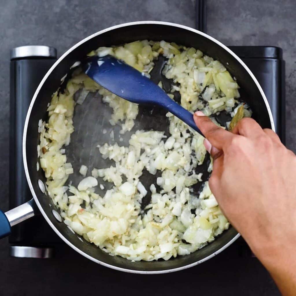 Sautéing the aromatics in a pan.