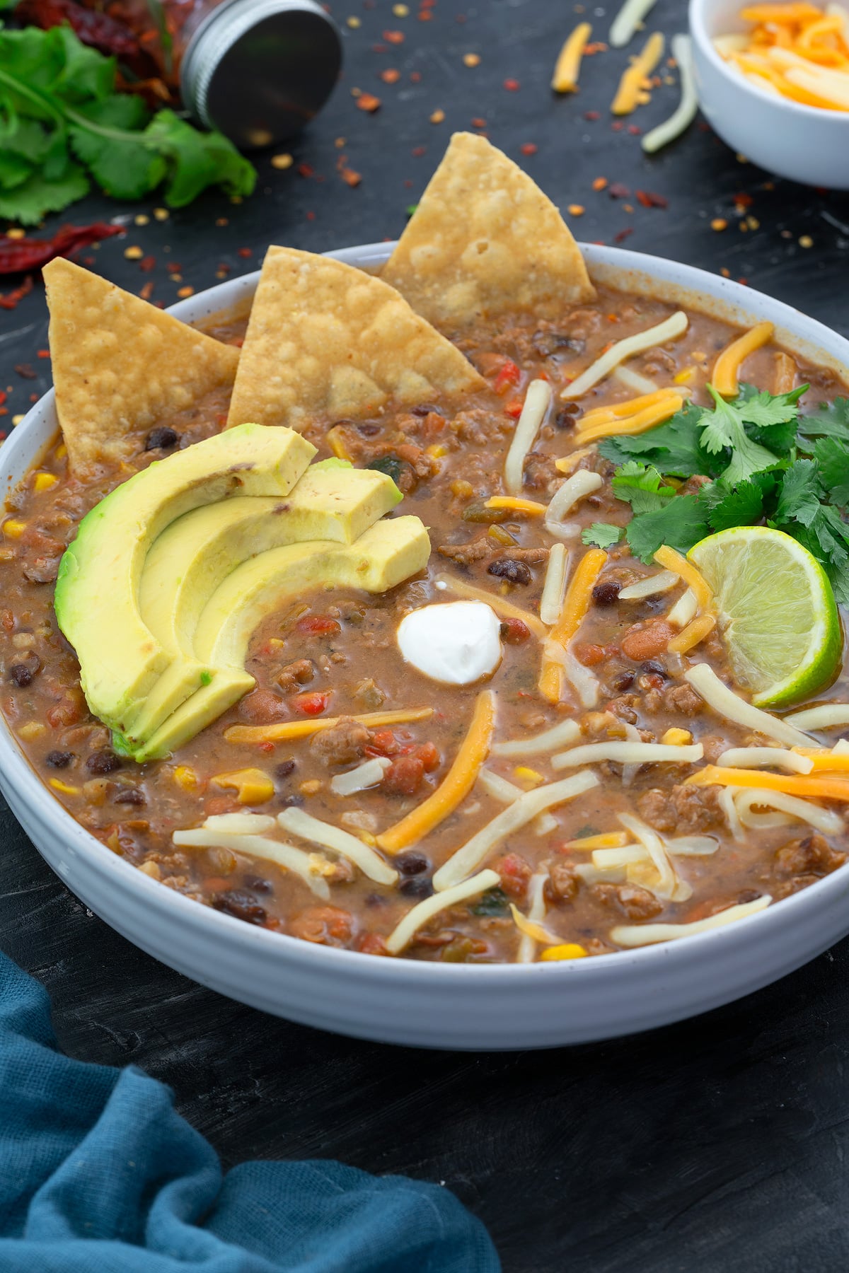 Turkey Chili in a white bowl with few ingredients scattered around.