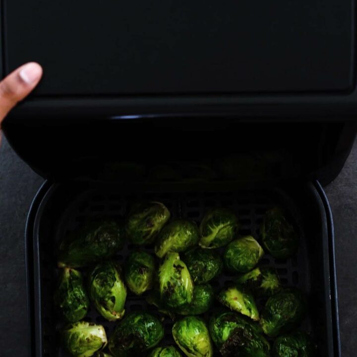 Shaking the air fryer basket with brussels.