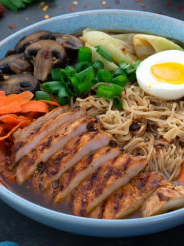 Chicken Ramen in a bowl with sliced chicken breast and boiled egg along with vegetables.