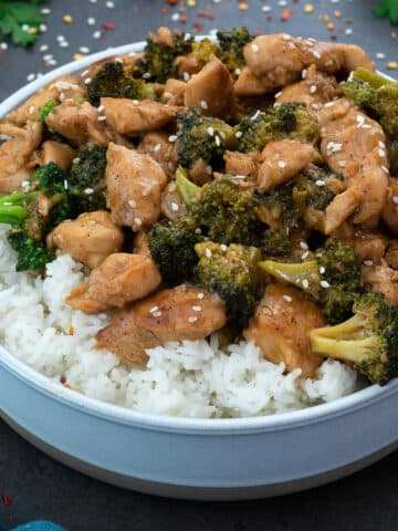 Chicken and Broccoli Stir Fry in a white bowl with few ingredients scattered around.