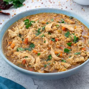 Chicken and Rice Soup in a bowl with few ingredients scattered around.