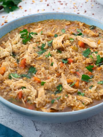 Chicken and Rice Soup in a bowl with few ingredients scattered around.