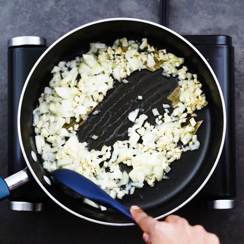 Sauteing the aromatics in a wide pan.