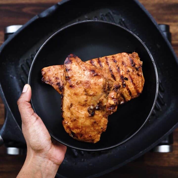 Grilled chicken breast on a black plate.