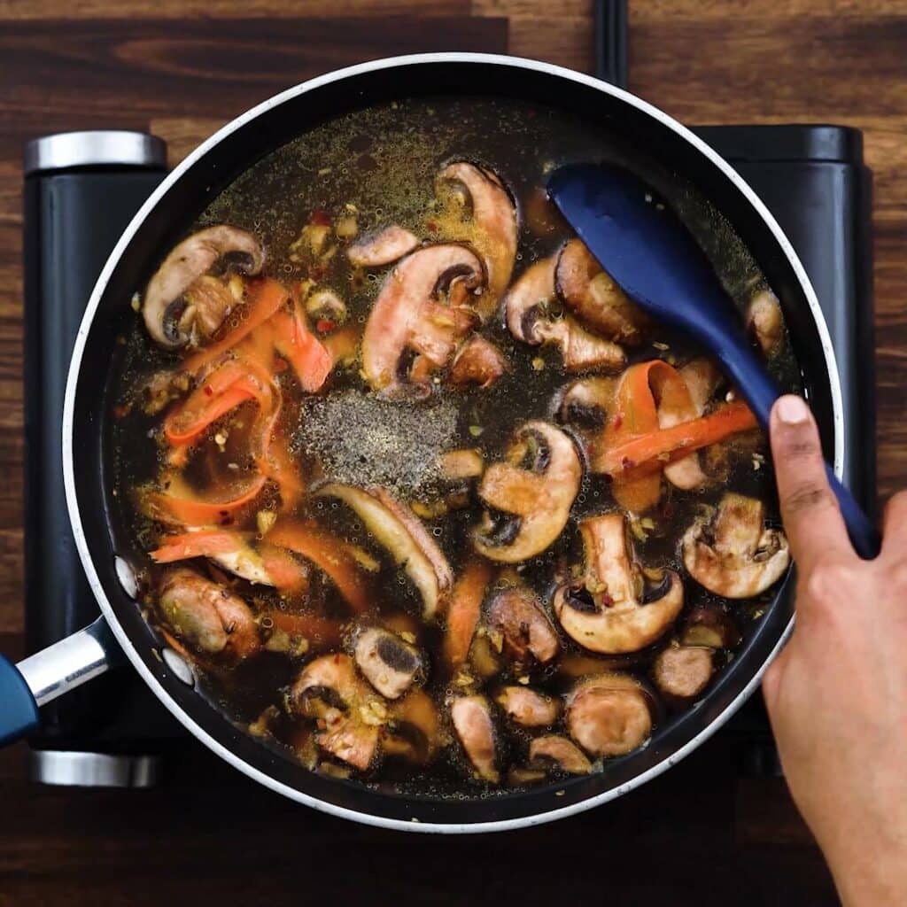 A pan with chicken broth and veggies.